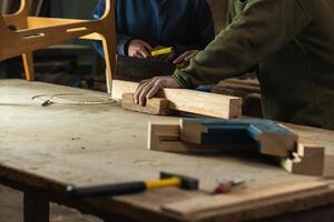 Joiner cutting wood with colleague measuring height photo