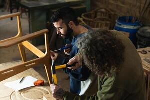 Male artisans creating wooden furniture in workshop photo