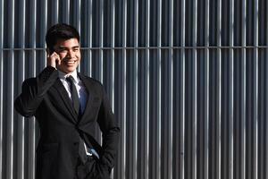 Smiling businessman speaking on smartphone in downtown photo