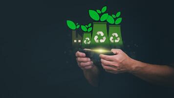 man holding smartphone with recycling symbol and plants on dark background photo