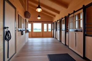 Horse stable interior showing empty stalls and tack room with hanging bridles photo
