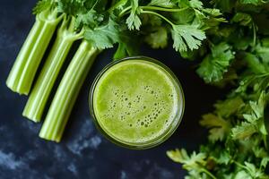 Glass of fresh celery juice with celery stalks on dark background photo