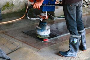 Worker polishing the marble tile with a grinder at the factory photo