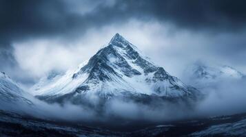 Majestic snow capped mountain peak emerging from misty clouds in winter landscape photo