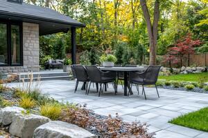 Dining table set on a modern stone patio in a backyard photo