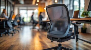 Ergonomic office chair stands empty in modern coworking space with blurred colleagues working photo