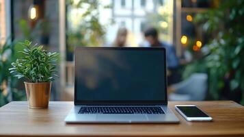Laptop and smartphone resting on table in cozy cafe setting with blurred patrons photo