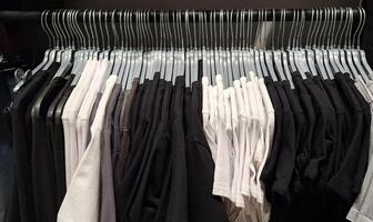 Black and white t-shirts on hangers in closet display photo