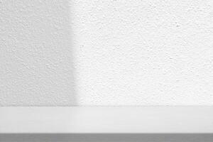 Blank Table with White Stucco Wall Texture Background with Light Beam and Shadow photo