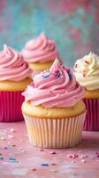 Three cupcakes with pink frosting on a pink background photo