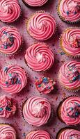 Pink cupcakes with sprinkles on a pink background photo