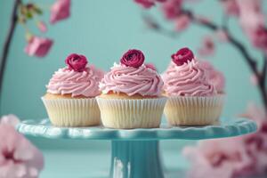 Three cupcakes with pink frosting on a blue cake stand photo