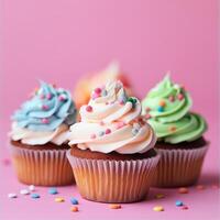 Three cupcakes with frosting on a pink background photo