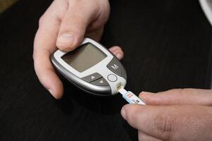 Close up man checking blood on sugar level. Home medical test. Concept of blood sugar level testing. photo