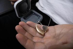 Close-up hearing aid on male hand with the its cover on background photo