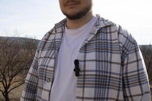A small buttonhole microphone on a man's shirt. The man fixed the mini microphone to his shirt photo