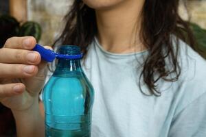 Bottle with stationary plastic cap in woman hand. The new design means the cap remains attached to the bottle after opening photo