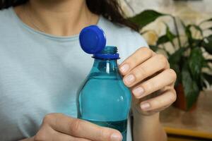 Opened bottle with stationary plastic cap and young woman in background. photo