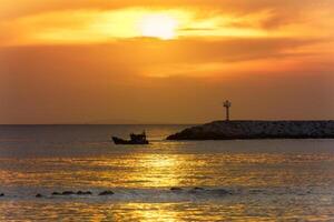 A boat is out in the ocean at sunset photo