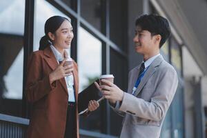 Asian business couple having coffee and talking outside photo