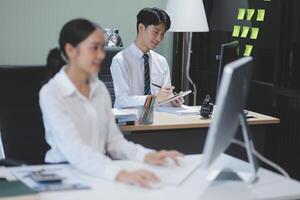 A man and woman sitting at a desk in front of a computer photo