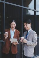 Two business people standing on a ledge with their phones photo