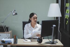 A woman is sitting at a desk with a computer photo
