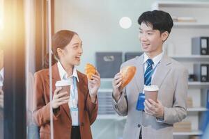 Asian business couple eating breakfast in office photo