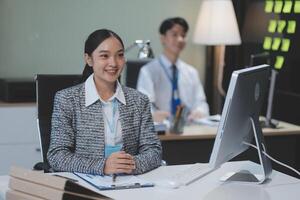 A woman in a business suit sitting at a desk with a computer photo