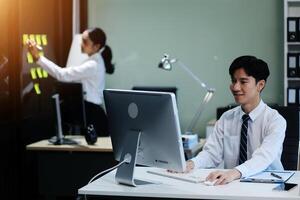A man and woman working on a computer in an office photo