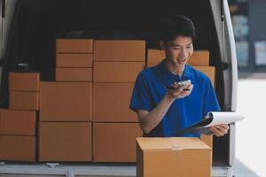 A young man in a blue shirt is standing in front of a van with boxes photo