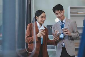 Two business people in suits holding coffee and looking at a computer screen photo