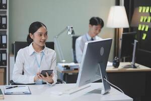 A woman sitting at a desk with a computer and a phone photo