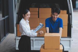 A man and woman are standing next to a truck with boxes photo