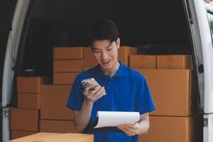 A man in a blue shirt holding a clipboard and looking at his phone photo