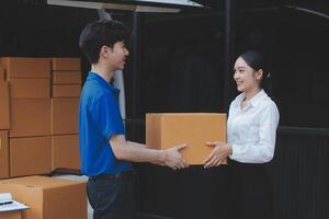 A man and woman are holding a box in front of a moving truck photo