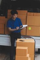 A man in a blue shirt and hat sitting on a box photo