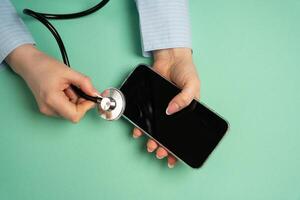 A woman listens to a telephone with a stethoscope. Diagnostics and repair. Identifying technical issues, diagnosing device malfunctions. Troubleshooting communication problems. Tech support photo