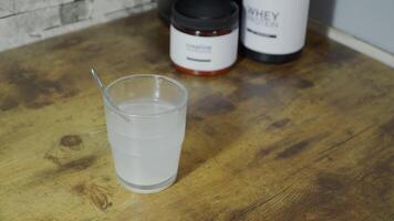 Creatine dissolving in water with whey protein beside video