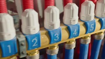 Underfloor heating manifold with control valves, flow meters and connected red pipes. Home heating system, plumbing and temperature control concept video