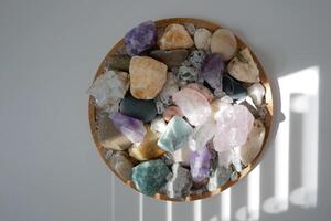 Stones, minerals, crystal, pebble on a round stand on a white background with shadow and light from blinds. the concept of interior details or esoteric rituals and meditation photo