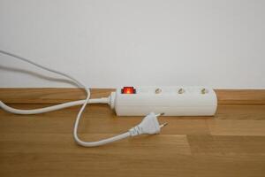 The electric cable is lying next to power strip socket extension cord photo