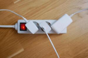 Three electric cables are plugged into a power strip extension cord photo
