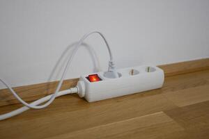 The electric cable is plugged into a power strip socket extension cord photo