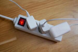 Three electric cables are plugged in power strip socket extension cord photo