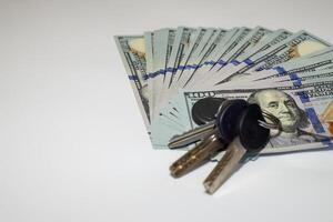 Dollar bills spread on a white background with apartment keys, real estate investment concept photo
