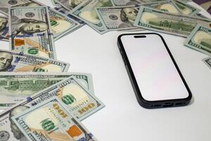 Currency arranged around a smartphone on a white surface in a composition on the theme of money, business, marketing, bank photo