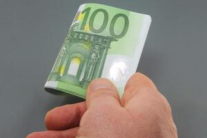 Hand Displaying Hundred Euro Banknotes on a Dark Background photo