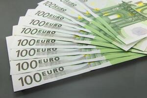 Stack of one hundred euro bills on a dark surface photo
