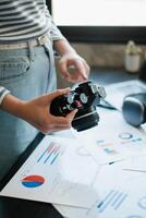 A person holding a vintage camera while reviewing business reports, blending creativity with strategic planning in a modern office. photo